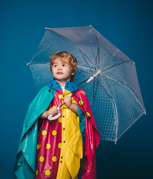 Garotinho com guarda-chuva colorido arco-íris isolado no fundo azul nuvem chuva guarda-chuva chovendo conc ...