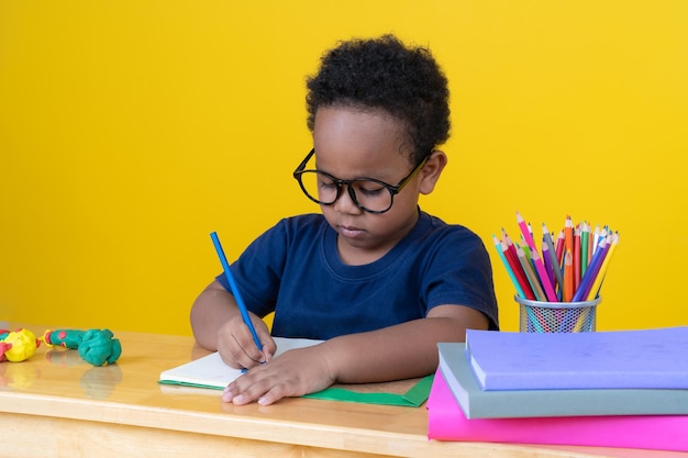 Garotinho com imaginação Sentado à mesa desenhando com lápis de cor