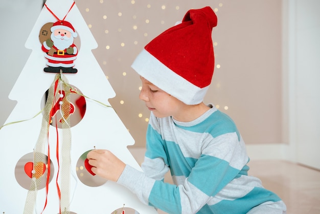 Garotinho com Papai Noel ao lado de uma árvore decorada