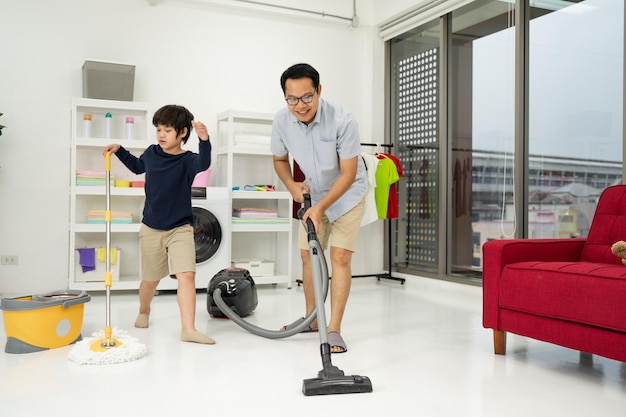Garotinho com seu pai usa aspirar o quarto Pai e filho fazendo a limpeza da casa