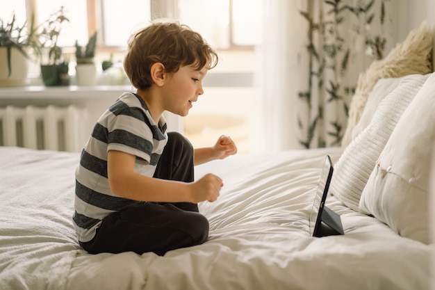 Garotinho com um tablet na sala.