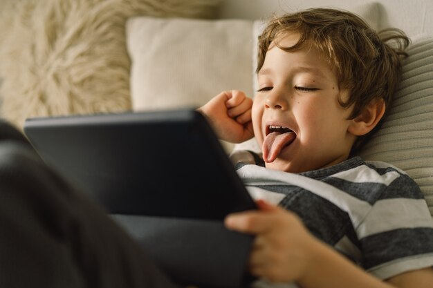 Garotinho com um tablet na sala.