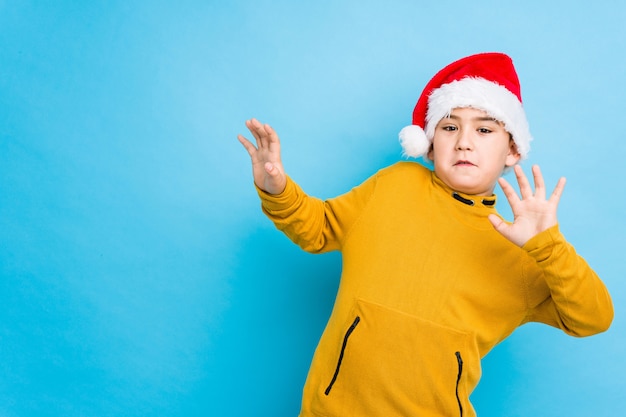 Garotinho comemorando o dia de natal usando um chapéu de papai noel isolado sendo chocado devido a um perigo iminente