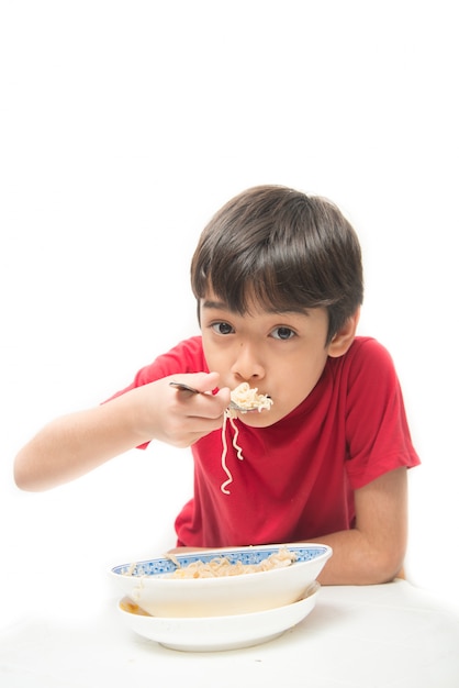 Garotinho comendo macarrão instantâneo com branco