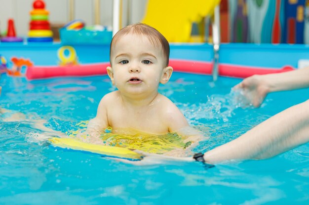 Garotinho de 2 anos está na piscina Aulas de natação para crianças pequenas