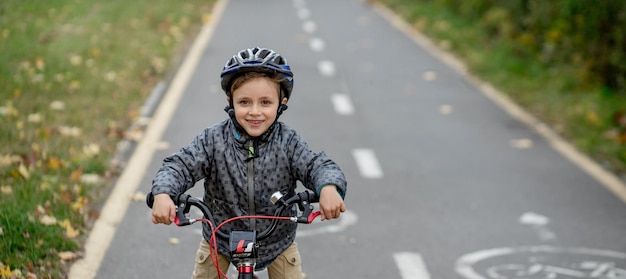 Garotinho de capacete em uma bicicleta anda em uma ciclovia no parque