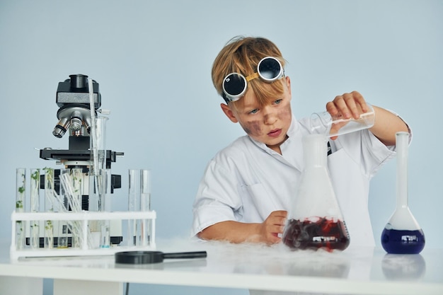 Garotinho de casaco jogando um cientista no laboratório usando equipamentos