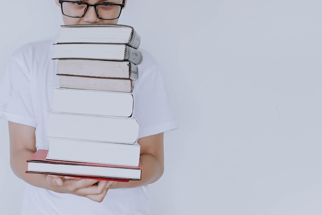 Garotinho de óculos segurando a pilha de livros isolados no fundo branco com espaço de cópia