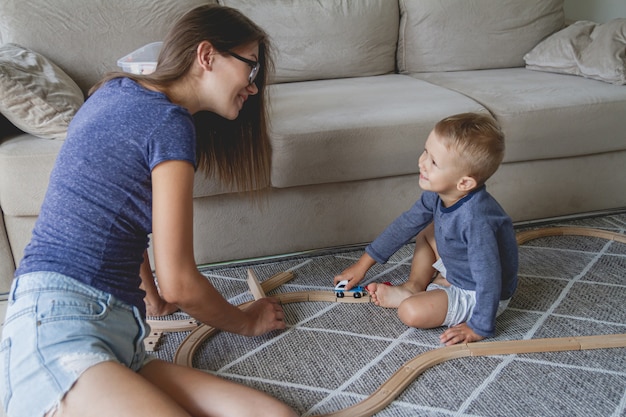 Garotinho e a mãe brincando com a ferrovia, sentado no chão