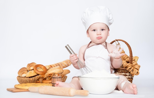 Garotinho em um boné de cozinheiro e com pão engraçado pequeno chef