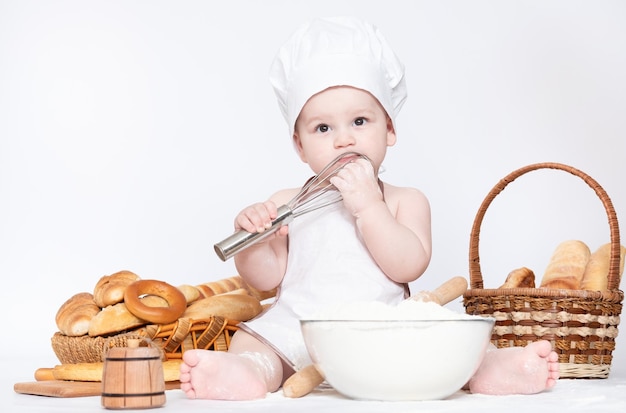 Garotinho em um boné de cozinheiro e com pão engraçado pequeno chef