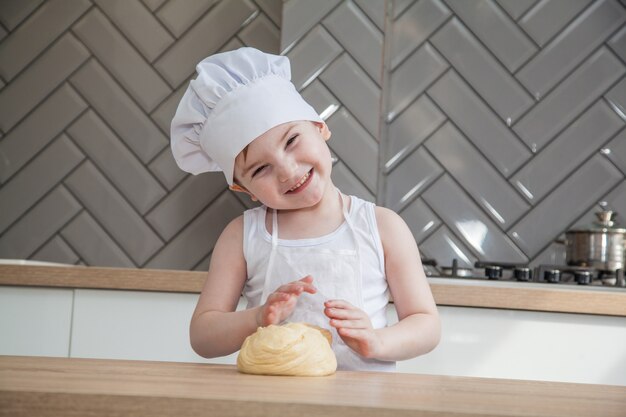 Garotinho em um chapéu de cozinheiro e avental na cozinha