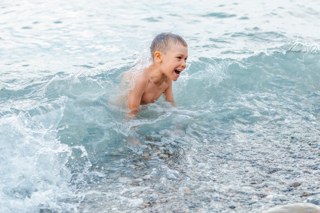 Garotinho em um maiô espirrando as pernas no mar