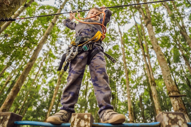 Foto garotinho em um parque de cordas recreação física ativa da criança ao ar livre no parque treinamento para crianças