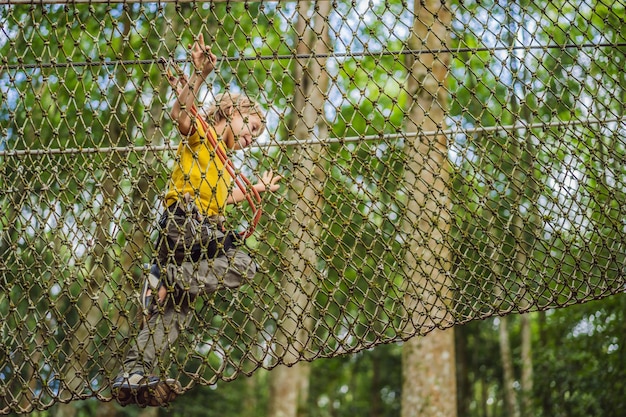 Garotinho em um parque de cordas Recreação física ativa da criança ao ar livre no parque Treinamento para crianças