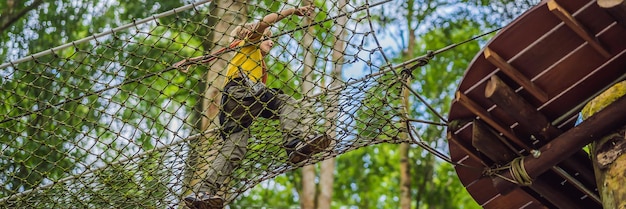 Garotinho em um parque de cordas recreação física ativa da criança ao ar livre no parque