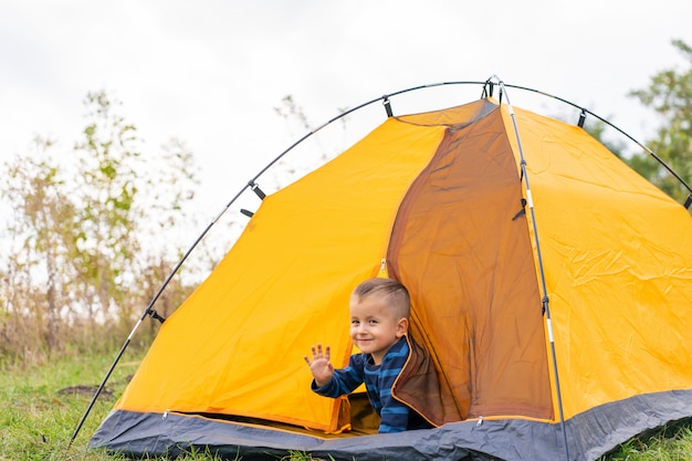 Garotinho em uma tenda. Acampar na natureza.