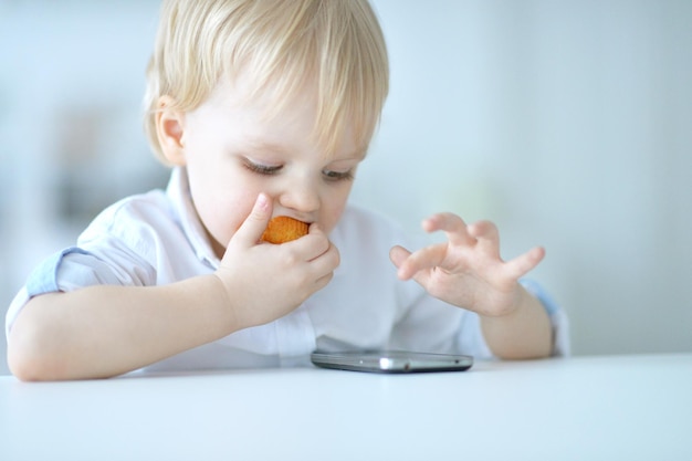 Garotinho está brincando com um telefone celular