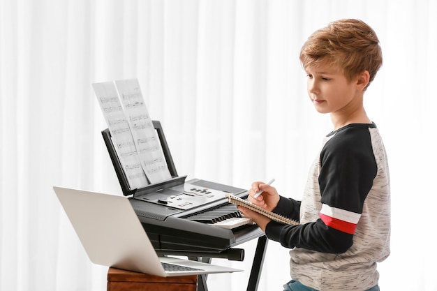 Garotinho fazendo aulas de música online em casa