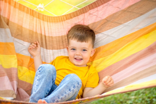 Garotinho feliz andando em uma rede brilhante em seu parque. Feriado de verão infantil