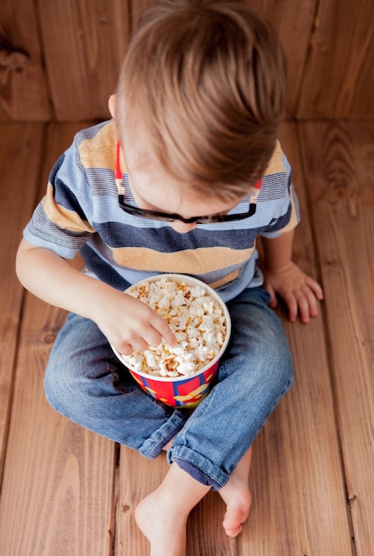 Garotinho fofo menino de 2 a 3 anos, óculos de cinema 3D imax segurando balde para pipoca