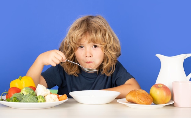 Garotinho jantando criança comendo sopa menino com colher comendo sopa bonito saudável com fome