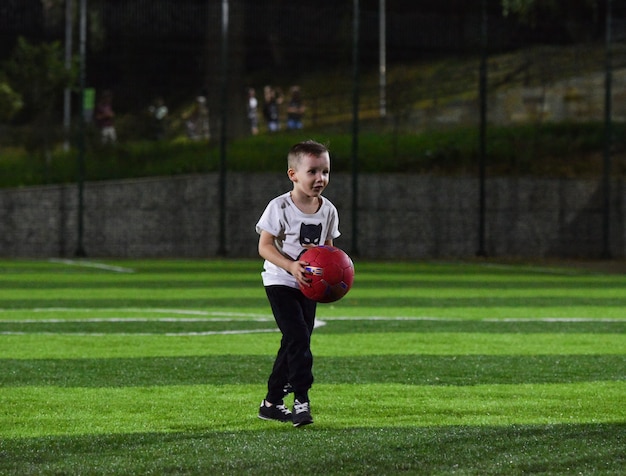 Garotinho jogando bola no campo de futebol, a noite e o crepúsculo