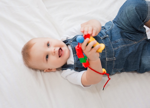 garotinho lindo está deitado na cama sorrindo e brincando