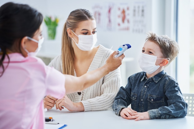 garotinho mascarado fazendo exame médico pelo pediatra durante a pandemia