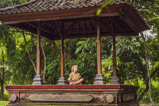 Garotinho meditar praticando ioga no gazebo tradicional de Bali.