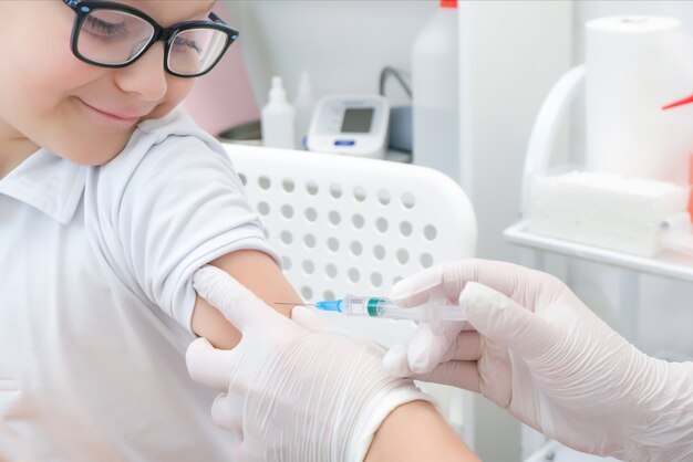 Garotinho recebendo vacinação na clínica, close-up. prevenção contra o vírus