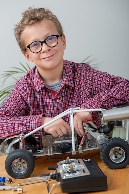 Garotinho, reparando um modelo de carro controlado por rádio em casa