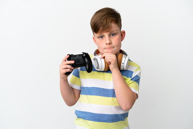 Garotinho ruivo segurando um gamepad isolado no fundo branco, tendo dúvidas e pensando