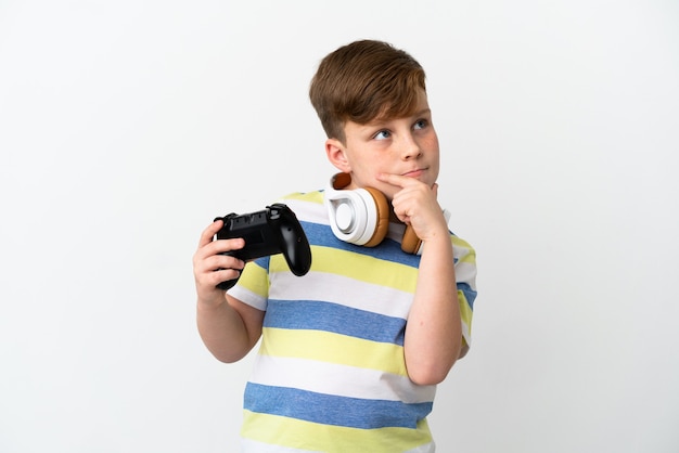 Foto garotinho ruivo segurando um gamepad isolado no fundo branco, tendo dúvidas