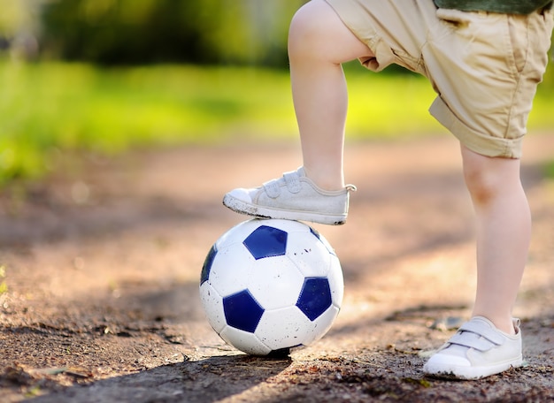 Garotinho se divertindo jogando futebol / futebol jogo no dia de verão