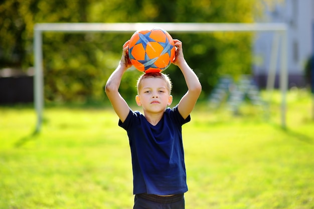 Foto garotinho se divertindo jogando um jogo de futebol no dia ensolarado de verão