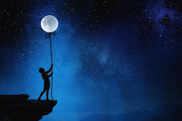 Foto garotinho segurando a lua à noite. mídia mista