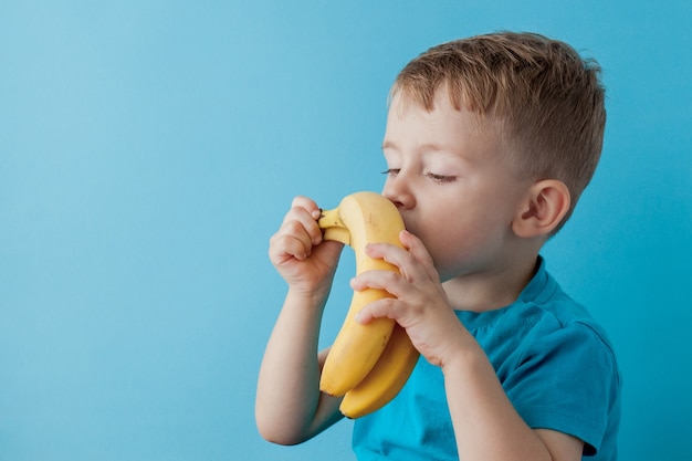 Garotinho segurando e comendo uma banana