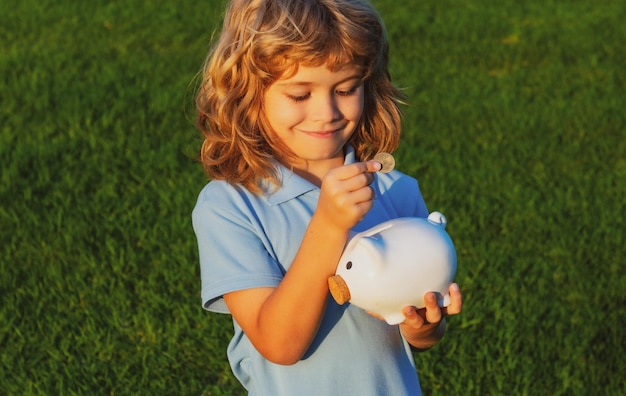 Garotinho segurando o cofrinho e sorrindo Retrato de menino criança segurando o cofrinho Economizando o conceito de dinheiro Criança feliz e alegre com o cofrinho cheio