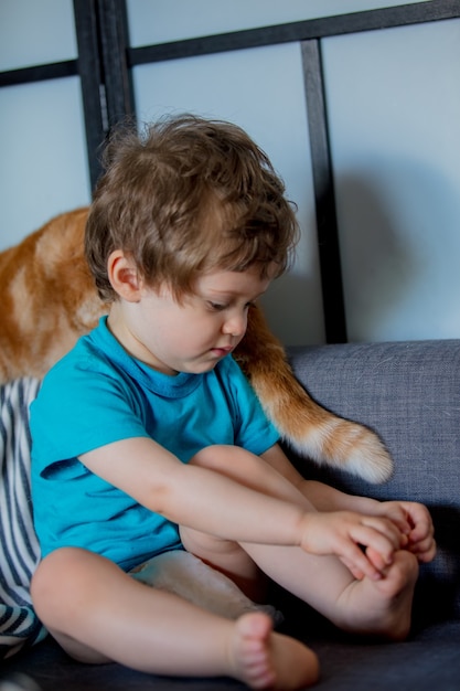 Garotinho segurando o pé dele depois de brincar com um gato