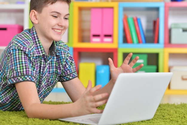 Garotinho usando laptop enquanto estava deitado no chão em casa