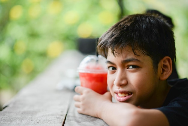 Garoto adolescente bebendo suco de frutas no parque acampando no horário de verão