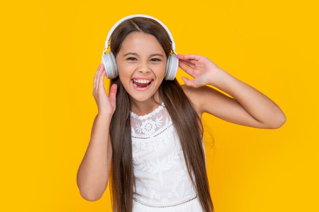 Garoto adolescente feliz ouve música em fones de ouvido em fundo amarelo