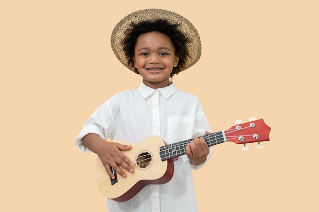 Foto garoto afro-americano feliz com ukulele em fundo amarelo