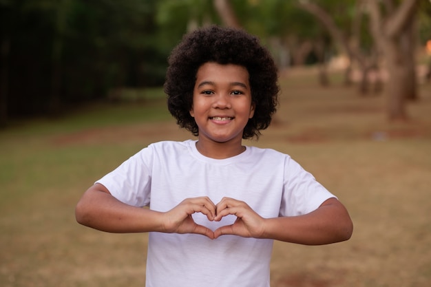 Garoto afro fazendo coração com a mão