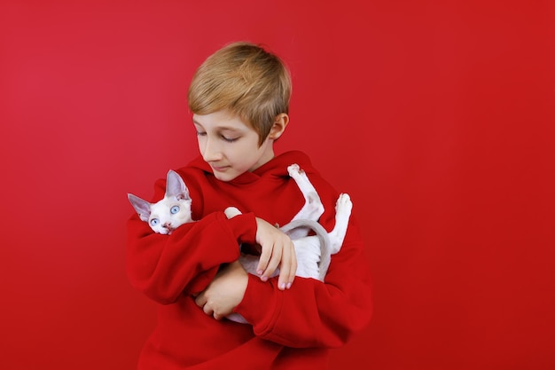 Garoto amoroso de terno vermelho segura um gatinho nos braços o abraça e o beija