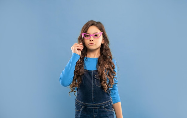 Garoto arrogante com cabelo longo encaracolado em fundo azul criança engraçada com óculos