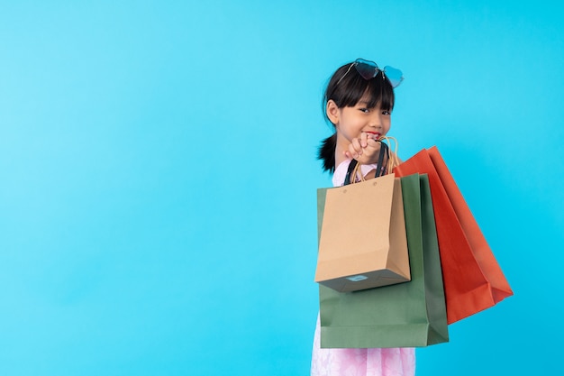 Garoto asiático jovem feliz elegante segurando o saco de compras, estilo de vida de pago pelo conceito de estilo de moda de crianças