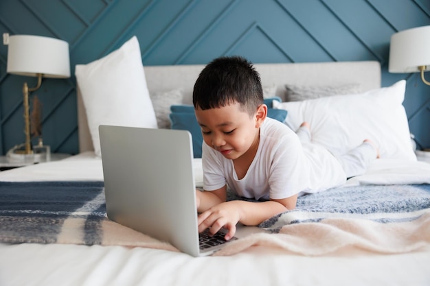 Garoto asiático usando estudo de laptop on-line com professor de videochamada no quarto para aprendizado à distância