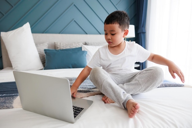 Garoto asiático usando estudo de laptop on-line com professor de videochamada no quarto para aprendizado à distância